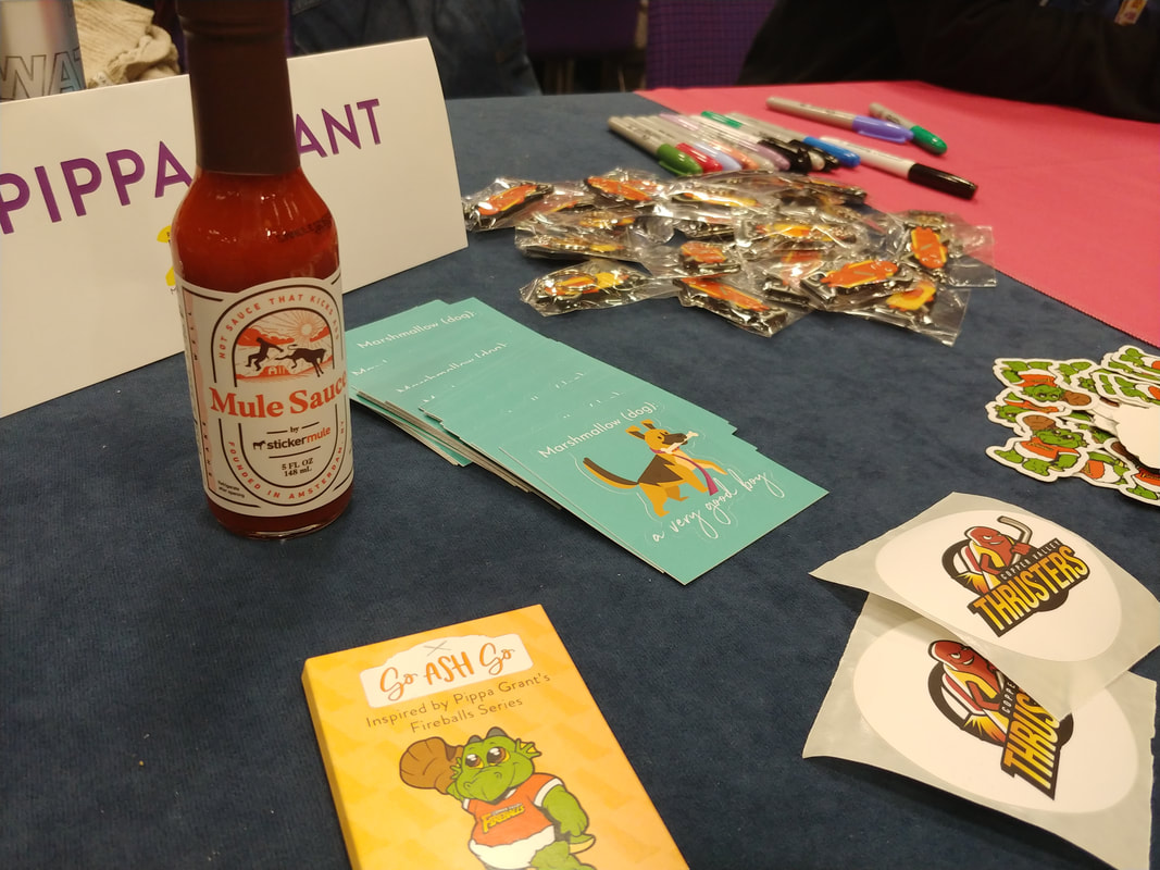 Pippa Grant's swag, including stickers, keychains, and a bottle of hot sauce